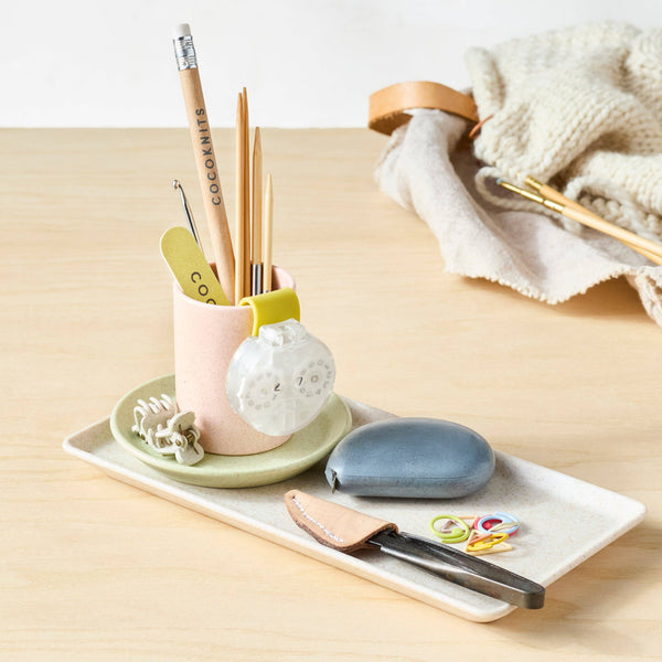 Desk organizer with stationery items on a light wooden surface