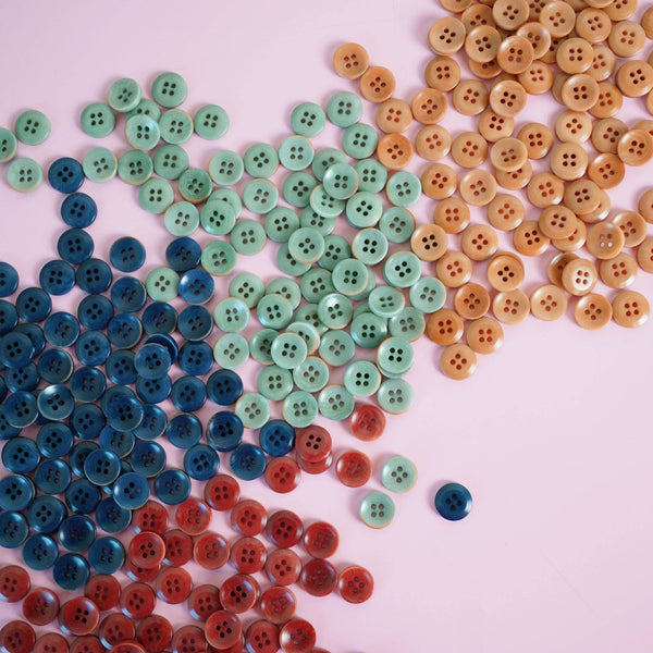 Assorted colorful buttons on a pink background