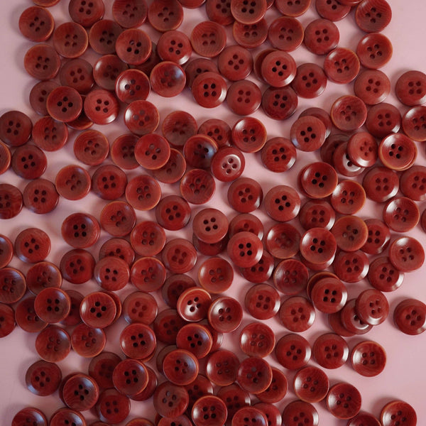 Large number of red buttons scattered on a pink background