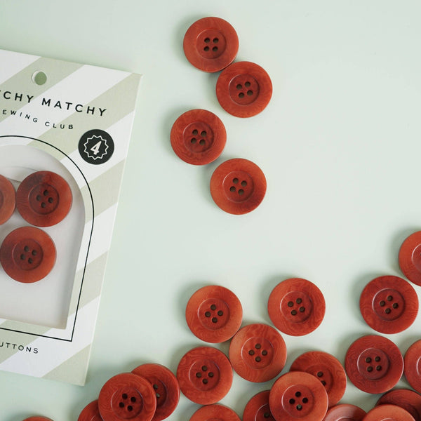Red buttons scattered on a light green surface with a 'Chy Matchy Sewing Club' package.