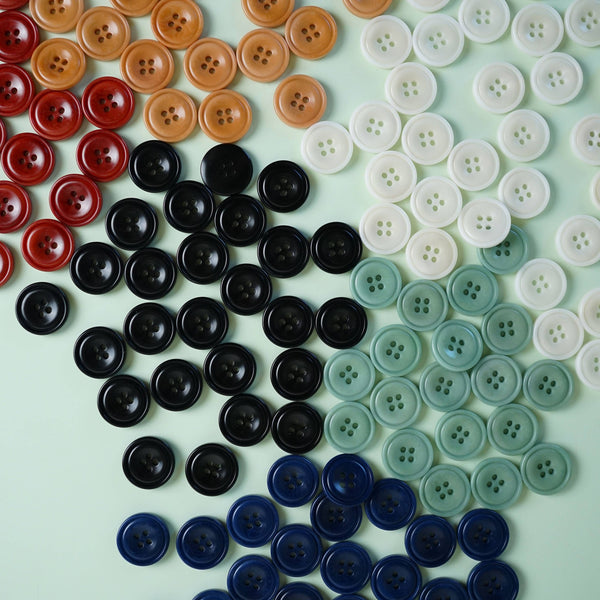 Assorted buttons in various colors arranged in a pattern on a light green background