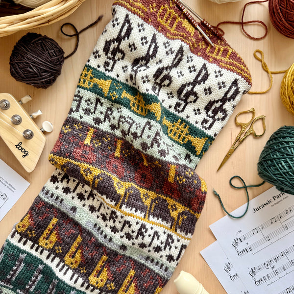 Knitted patterned fabric with yarn and knitting tools on a wooden surface