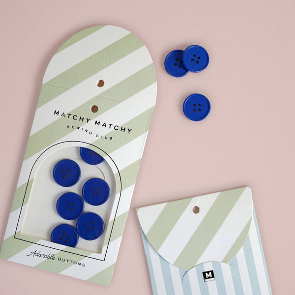 Blue buttons on a striped packaging with 'Matchy Matchy Sewing Club' branding on a pink background.