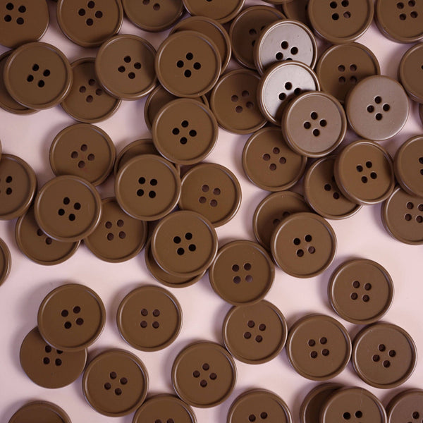 Brown buttons scattered on a light pink background
