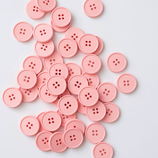 Pink buttons scattered on a light gray background