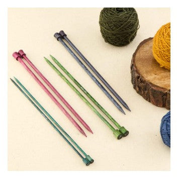 Set of colorful knitting needles on a light background with yarn balls.