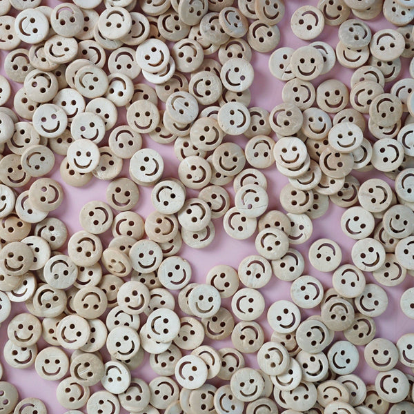 Beige smiley face buttons scattered on a pink background