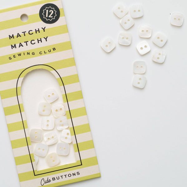 Packaging of Matchy Matchy Sewing Club buttons with buttons scattered on a white background