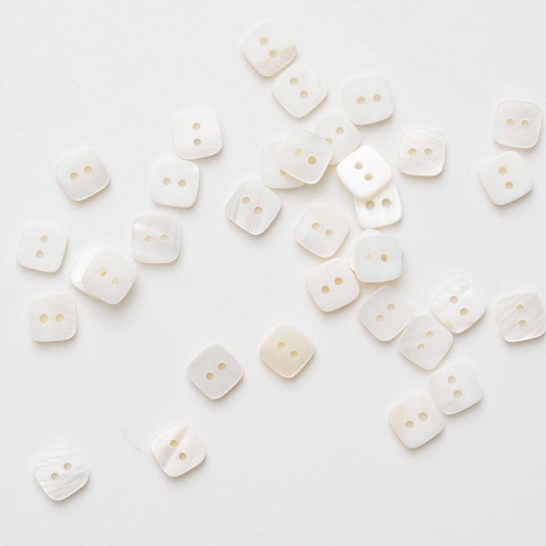 White buttons scattered on a white background