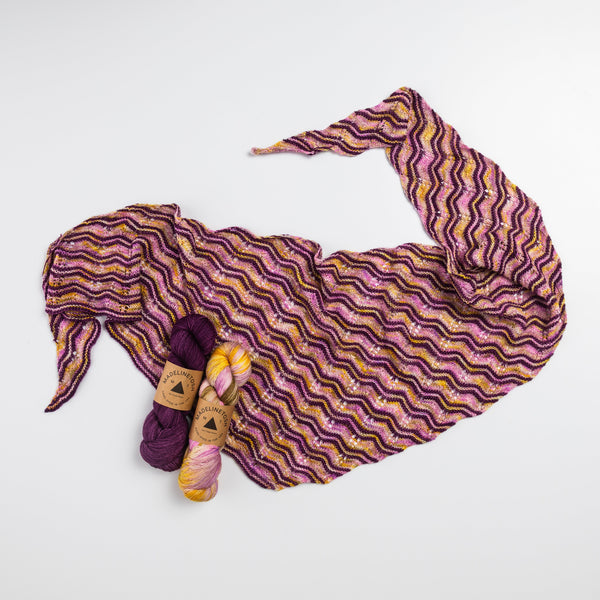 Knitted scarf with wavy pattern and two balls of yarn on a white background