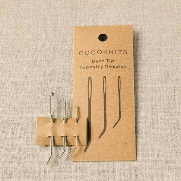 Cocoknits bent tip tapestry needles on a cardboard backing with 'Cocoknits' branding on a beige fabric background.