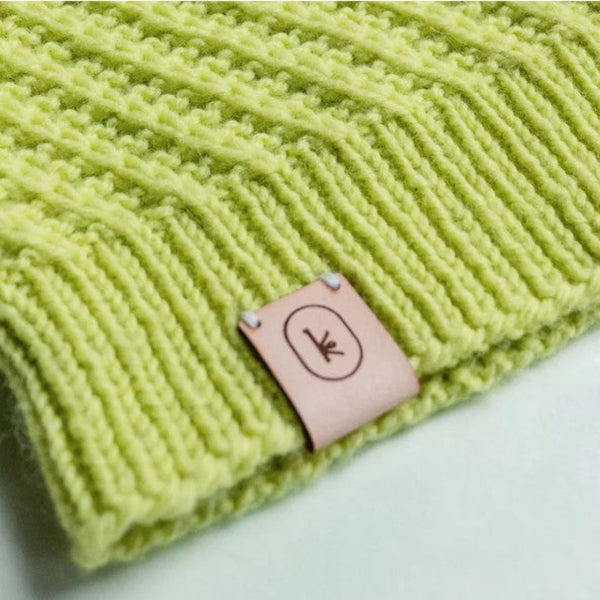 Green knitted fabric with a pink label featuring a logo on a white background