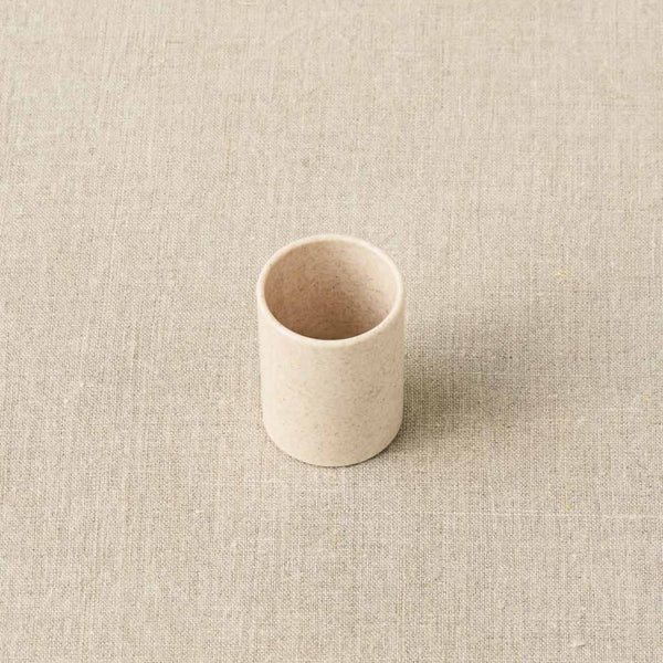Small beige ceramic cup on a textured beige background
